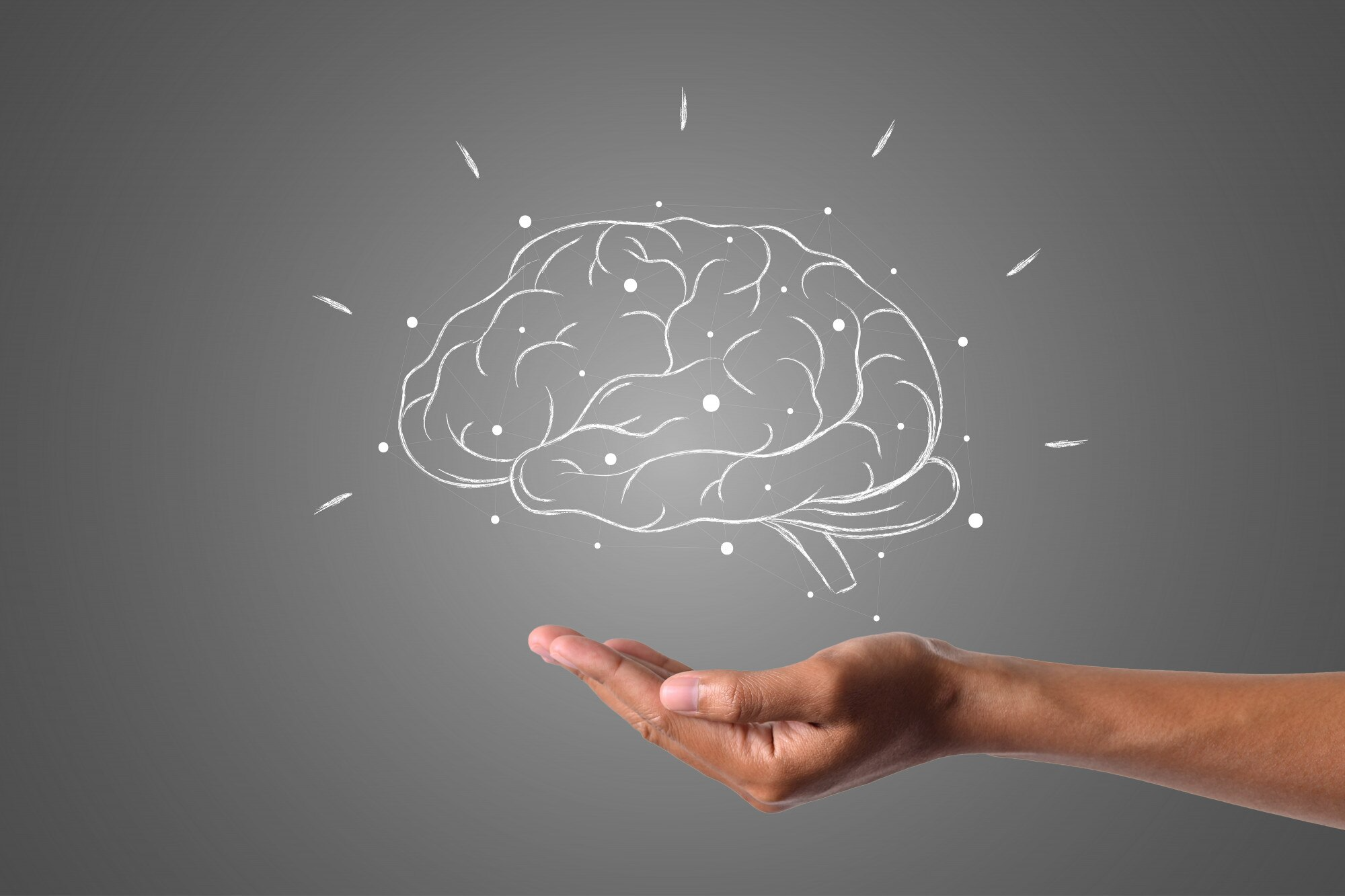 Cerebro brillando en pizarron con gis sobre una mano