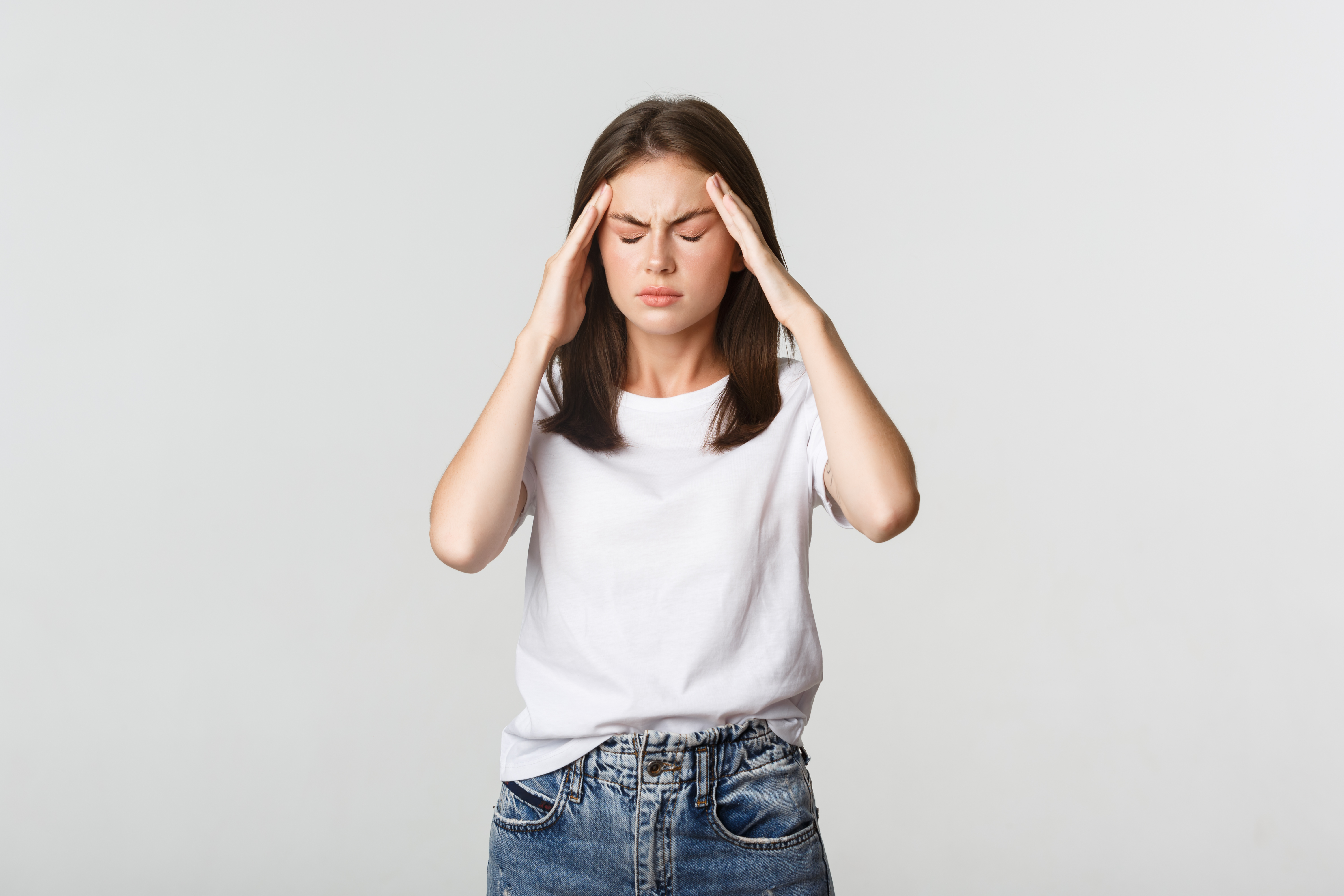 Mujer con playera blanca con dolor de cabeza/migraña crónica