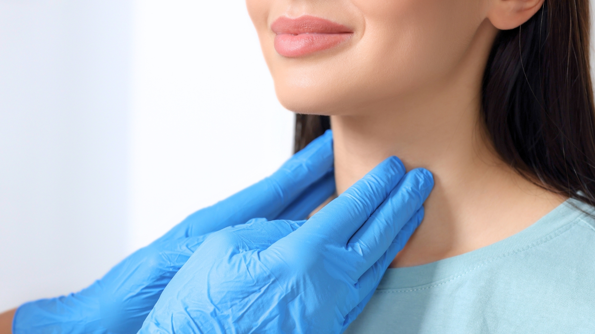 Doctor tocando lagarganta de paciente, palpando cuello mujer blanca, Tiroiditis de Hashimoto Sintomas y Causas